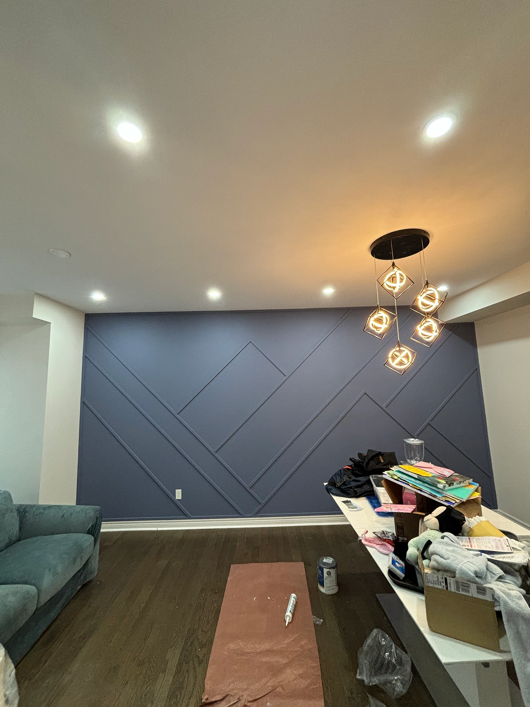 Completed deep blue geometric accent wall with modern pendant lighting