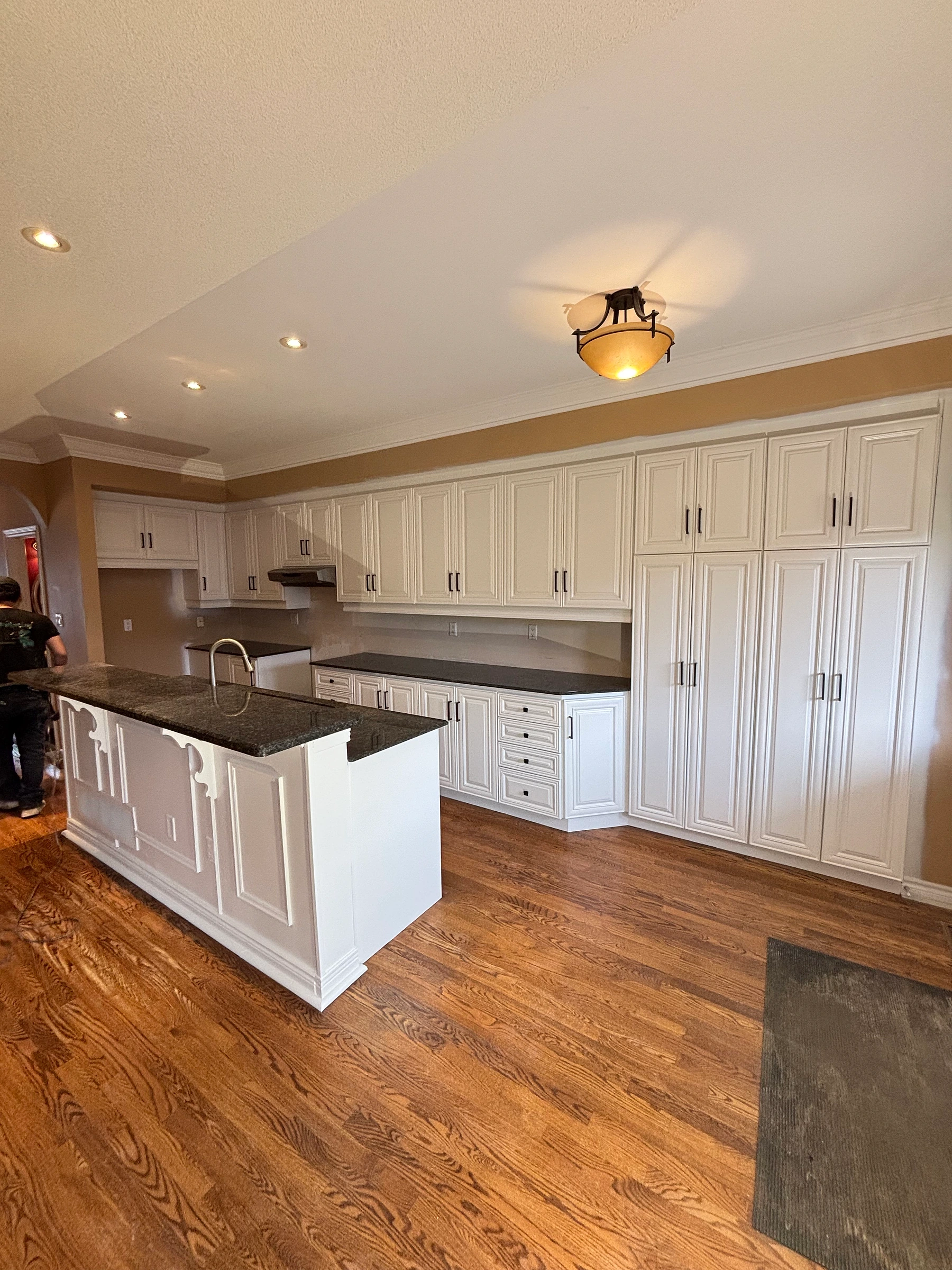 Large kitchen with professionally refinished white cabinets and black hardware