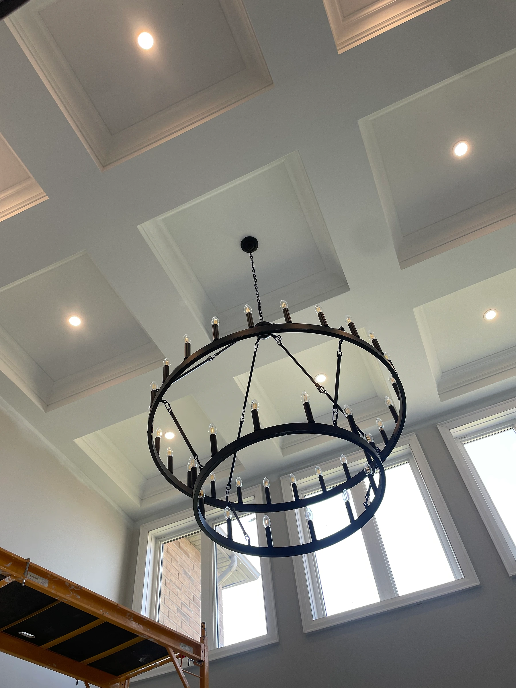 Finished high feature ceiling with white moulding, recessed lighting, and black chandelier