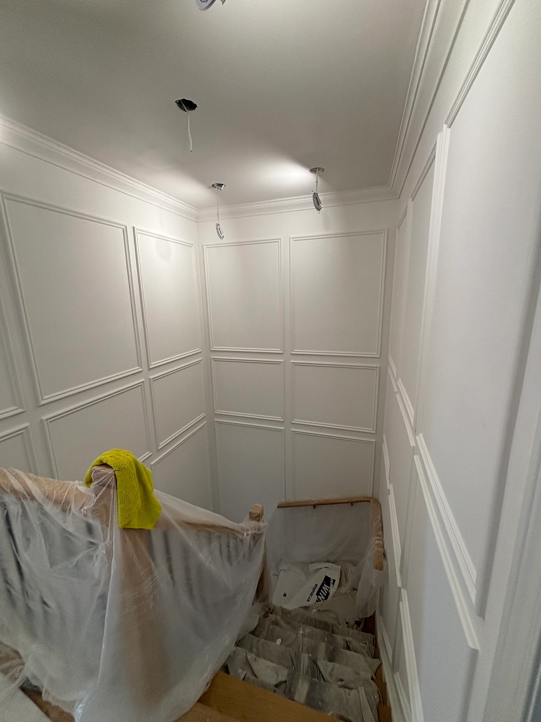 Freshly painted light wall moulding with protected staircase below